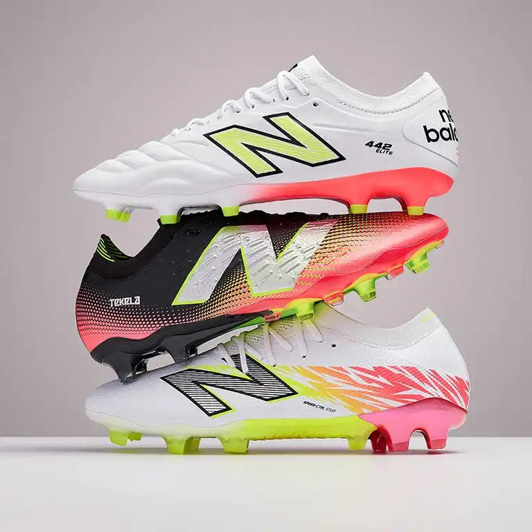 Image of Trois crampons de football New Balance empilés en blanc, noir et blanc avec des accents colorés.